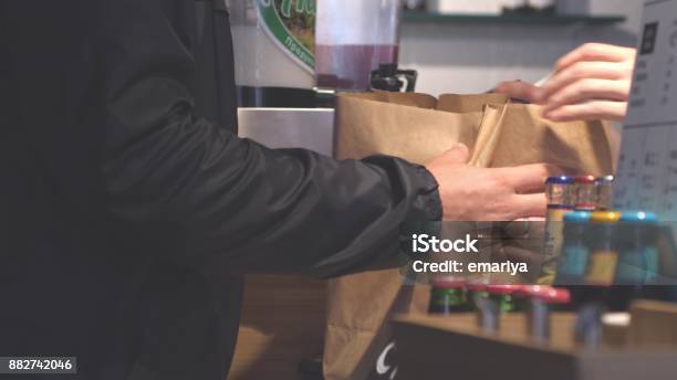 Hands Putting Burgers Into Bag Man Buys Packaged Food In Cafe Stock Photo - Download Image Now