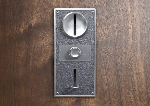A vintage metal coin receptacle slot panel from a coin operated machine with entry and exit slots mounted on a wooden surface