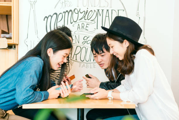 groupe d’amis en regardant smartphones - le monde des cafés photos et images de collection