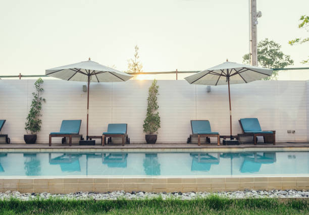 istock Blue sunbed with white umbrella on swimming pool 882753636