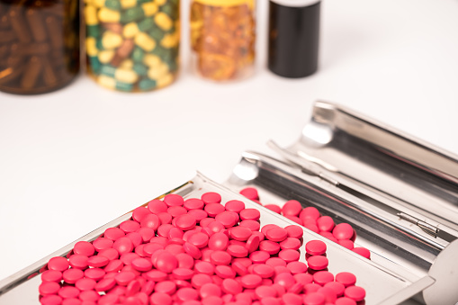 red medical drug on medical tray on white background