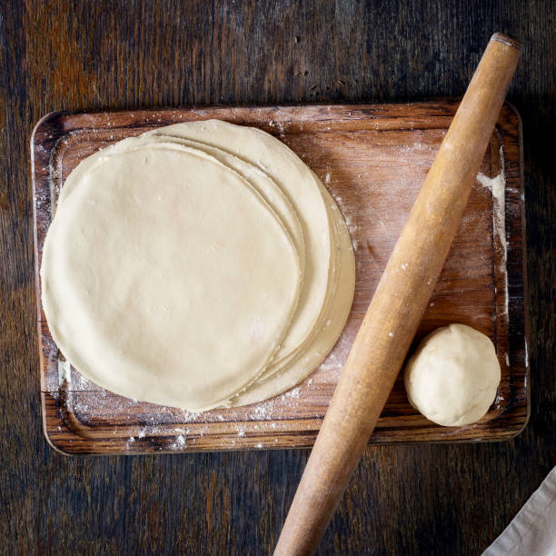 istock Raw fresh dough on a wooden board with rolling pin 882784686