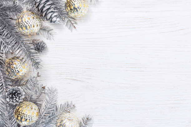 istock silver christmas tree branches decorated with glowing light garlands and pine cones on white wooden desk 882791948