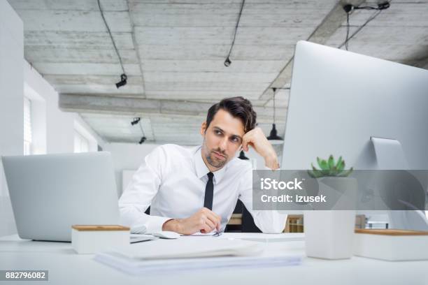 Pensive Businessman Sitting At His Office Desk Stock Photo - Download Image Now - Adult, Adults Only, Business