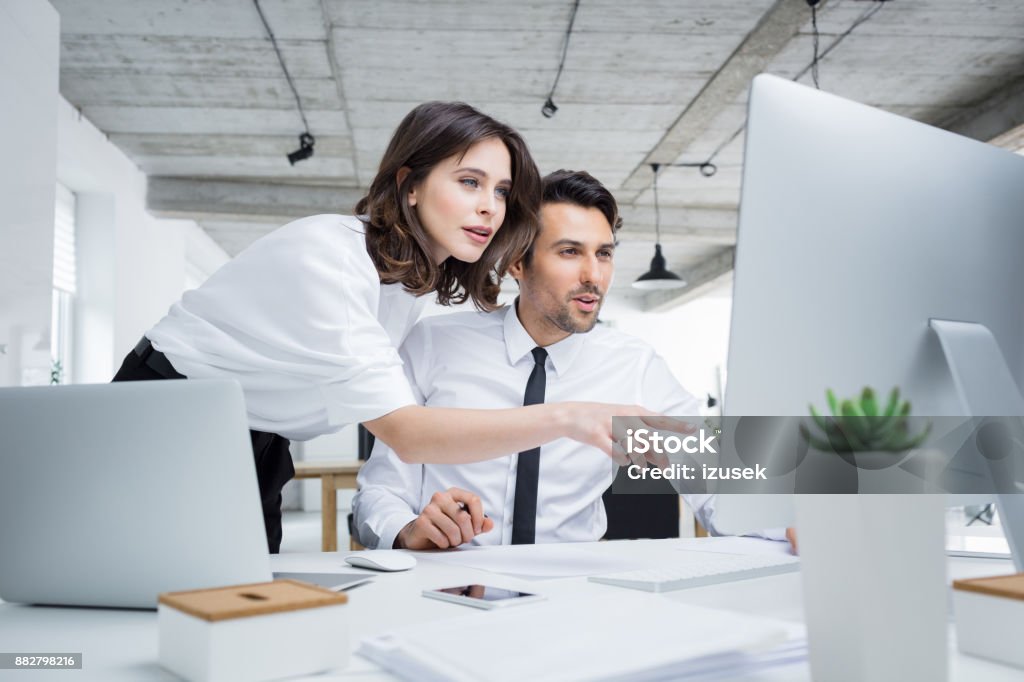 Business people working together on computer Two business people working together on computer. Businessman and businesswoman looking at computer monitor in office. Office Stock Photo