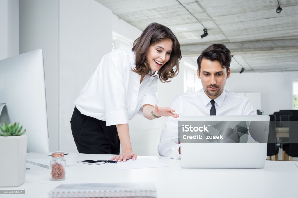 Happy business people working together on laptop Happy business people working together on laptop. Businessman and businesswoman looking at laptop and smiling in office. Businesswoman Stock Photo