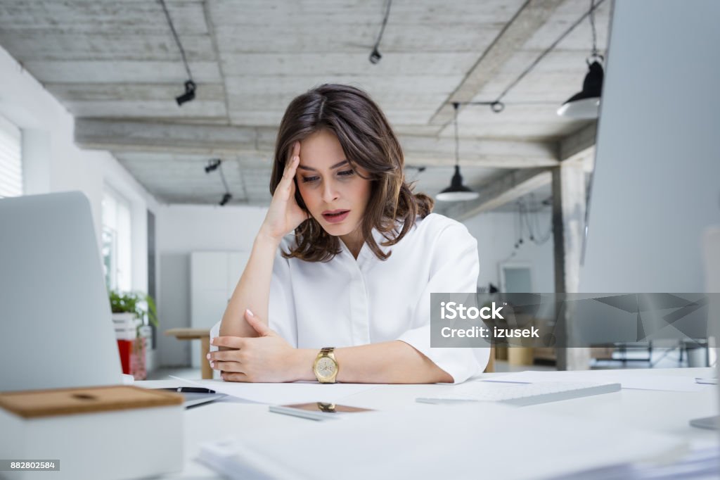 Female entrepreneur with headache sitting at desk Female entrepreneur with headache sitting at desk. Businesswoman under terrible physical tension at work. Working Stock Photo