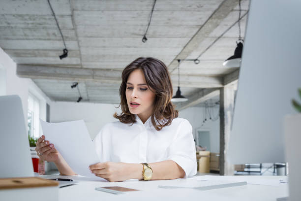 inquiet femme d'affaires lisant un document - beautiful office people shock photos et images de collection