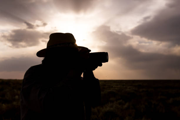 istock silhouette of a man with a camera on a sunset background 882809802