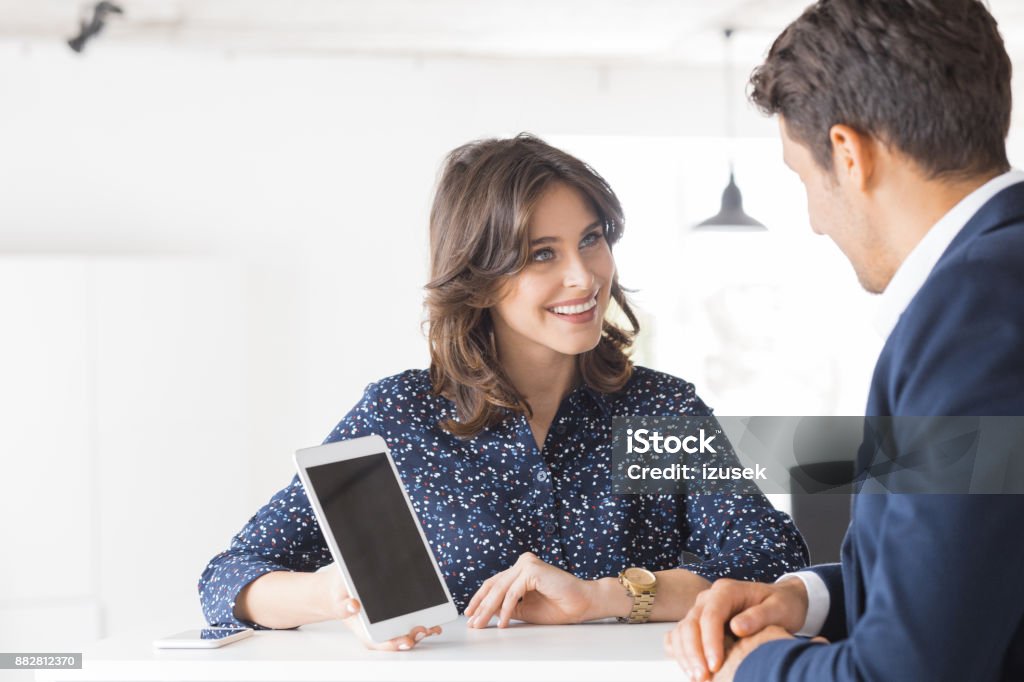 Two business people working together in office Smiling woman showing a proposal on digital tablet to businessman. Two business people working together at office using digital tablet. 20-29 Years Stock Photo