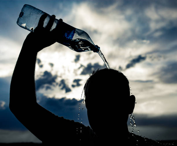 istock man pours water on his head in the sunset 882812374