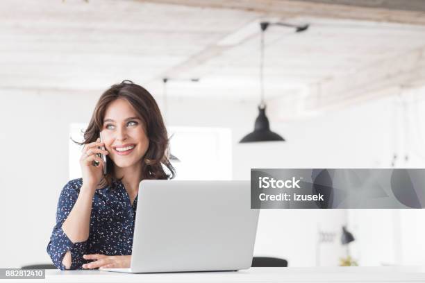 Beautiful Woman Talking On Phone At Office Stock Photo - Download Image Now - Businesswoman, Modern, Occupation