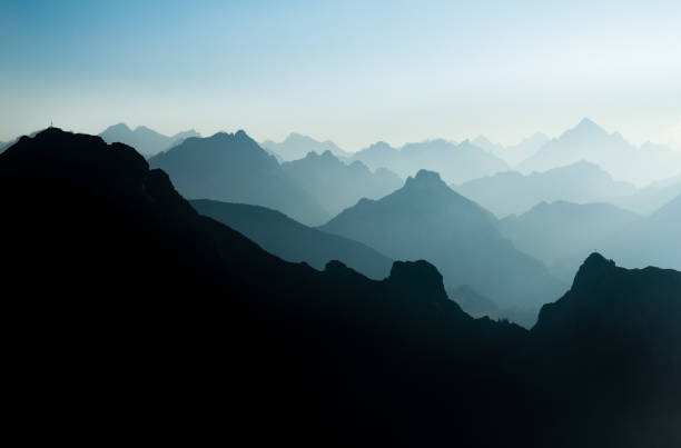 istock Spectacular blue and cyan mountain ranges silhouettes. Summit crosses visible. 882812514