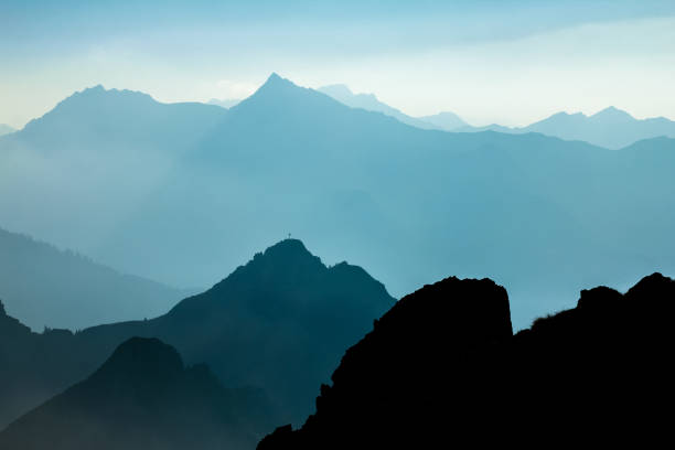 istock Spectacular blue and cyan mountain ranges silhouettes. Summit crosses visible. 882812794
