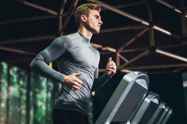 Man running at the gym Man running in a gym on a treadmill concept for exercising, fitness and healthy lifestyle treadmill photos stock pictures, royalty-free photos & images