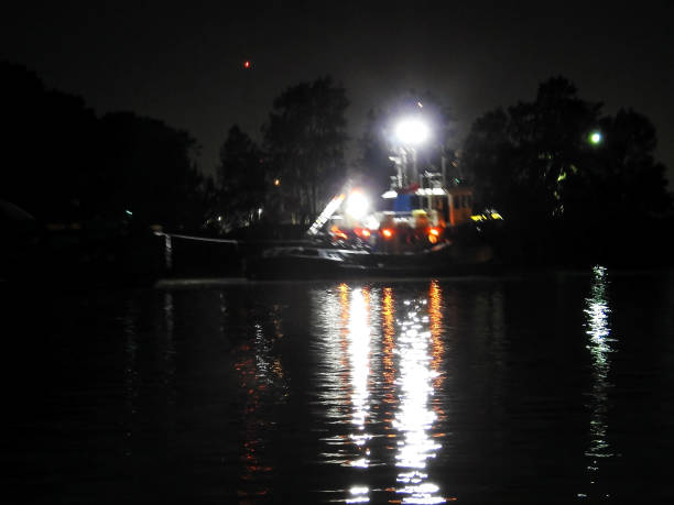 A tug boat with bright lights in the river at night.