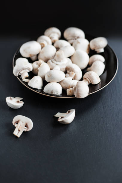 istock Mushroom champignon on dark   background, sliced and whole with copy space. Cooking delicious organic mushroom. Gourmet food 882824542