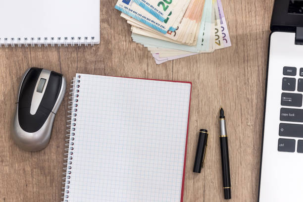 istock laptop, pen, euro banknote and notepad on desk. 882825060