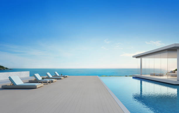 maison de plage de luxe avec piscine de la vue mer et terrasse dans un design moderne, les chaises longues sur plancher en bois du pont à domicile ou hôtel illustration de 3d - vacances de l’extérieur de villa de vacances contemporaine - bâtiment vu de lextérieur photos et images de collection