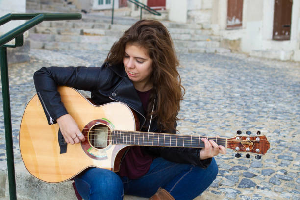 istock Content Young Woman Playing Guitar on Street 882827626