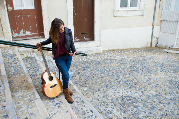 istock Pretty Female Guitarist Using Smartphone on Street 882827662