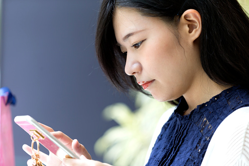 Japanese girl at a cafe checking her smart phone for latest social media messages