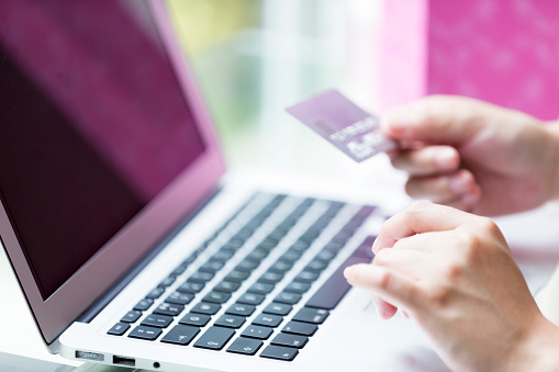 Young girl holding her credit card and shopping online using her laptop