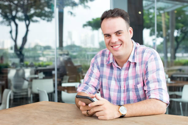 istock Smiling Man Using Smartphone in Outdoor Cafe 882831240