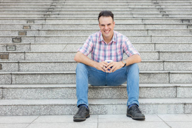 istock Smiling Young Man with Drink on Stairway 882832004