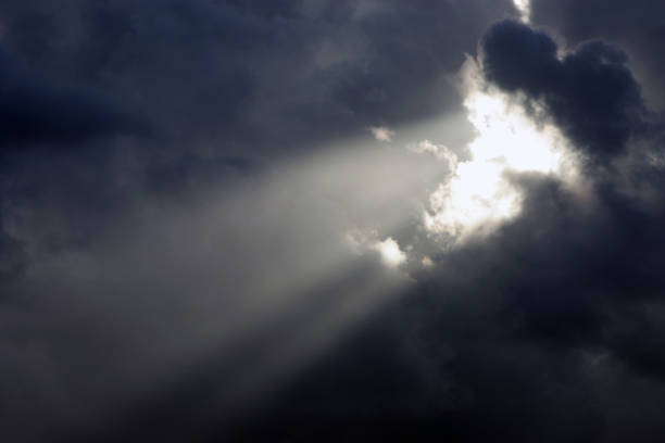 istock Rays of the sun shine trough dark clouds 882847414