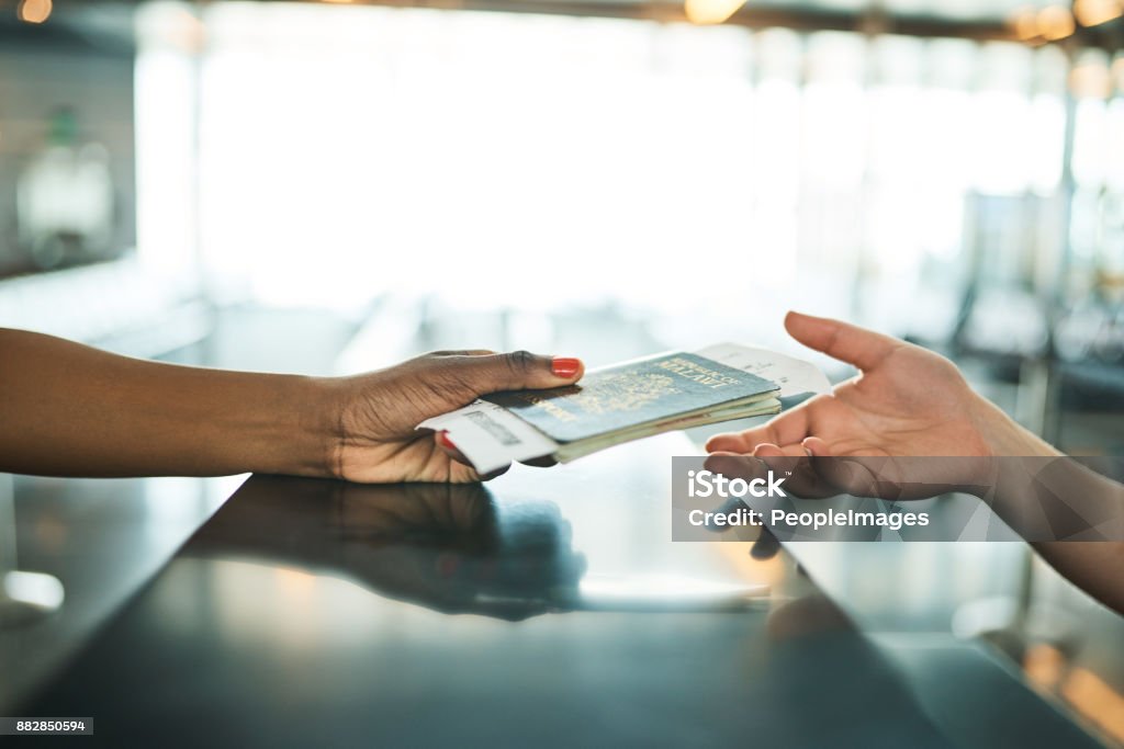 Her travel documents are in order Cropped shot of an unrecognizable woman handing over her ID book at a boarding gate in an airport Customs Stock Photo