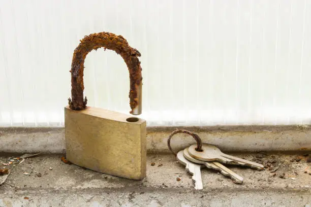 A lock and a set of keys look totally deteriorated and unusable due to the effect of the humidity and corrosion to which they were exposed when being abandoned in the window of a garage.