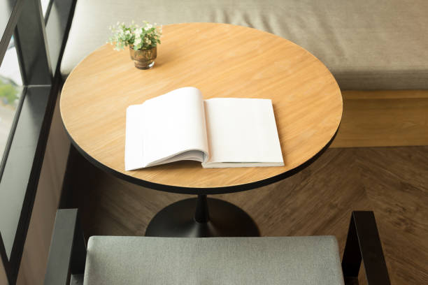 istock Wooden table with an opened book and plant on window 882865868