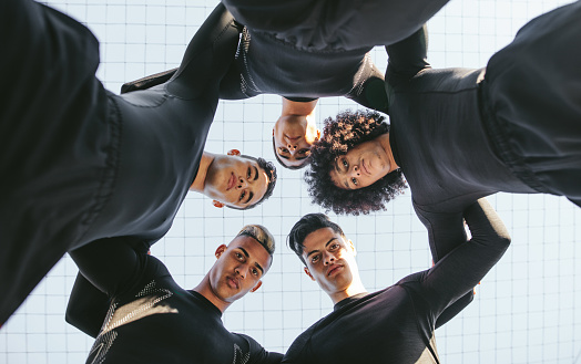 Low angle view of five a side football team huddle. Young soccer player standing in a circle.