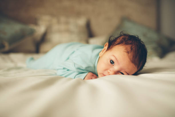 mignon petit bébé garçon couché sur le lit - être étendu sur le ventre photos et images de collection