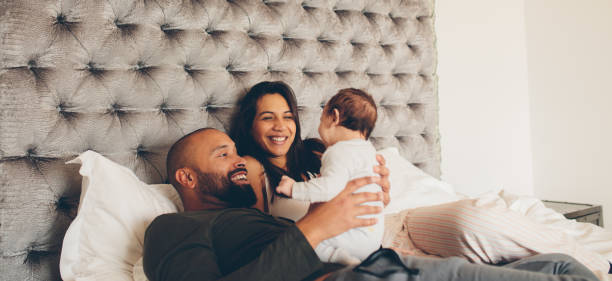 Happy parents playing with their newborn son on bed Happy parents playing with their newborn son on bed at home. Couple with little baby boy on bed. biracial newborn stock pictures, royalty-free photos & images