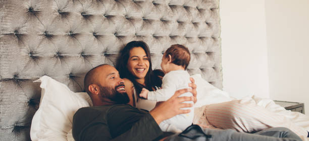 Happy parents playing with their newborn son on bed Happy parents playing with their newborn son on bed at home. Couple with little baby boy on bed. lifestyle newborn stock pictures, royalty-free photos & images