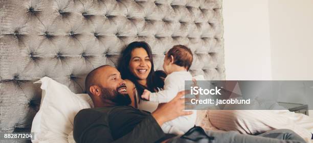 Happy Parents Playing With Their Newborn Son On Bed Stock Photo - Download Image Now