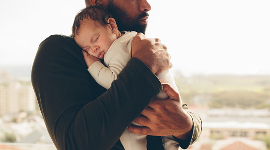 Man carrying his sleeping son. Newborn baby boy in his father's arms.