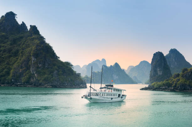 Lush tropical plants, island limestone mountains, blue water, and boats view along the ocean sea at Halong Bay in Vietnam. Photo taken on a cloudy day