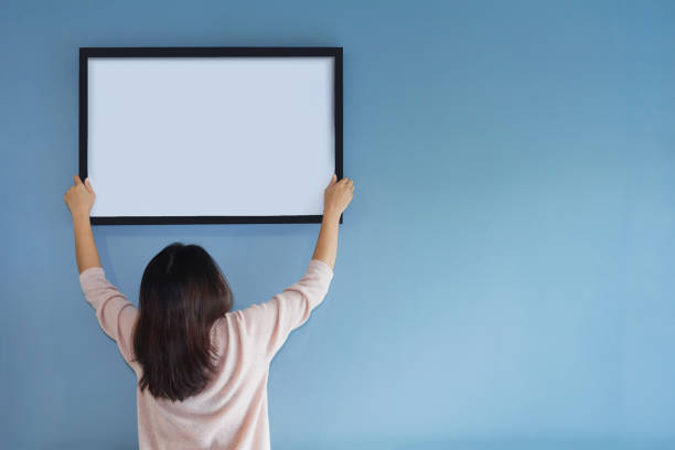 istock Asian woman holding a picture frame on blue wall. 882874664