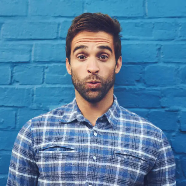 Cropped shot of a handsome young man posing against a blue wall