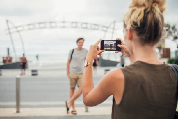 A woman photographs her boyfriend with her smartphone in Surfers Paradise - Queensland, Australia.