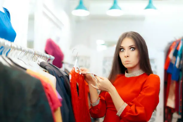 Funny shopper girl is amazed by the costs of a fashion item