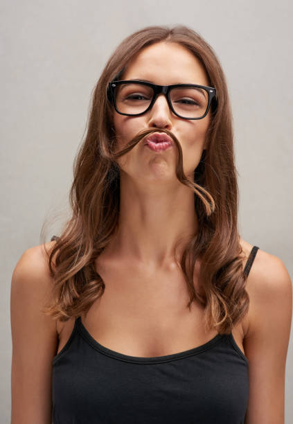 Looks like it's Movember again Studio portrait of an attractive young woman posing with her hair over her lip against a grey background women movember mustache facial hair stock pictures, royalty-free photos & images
