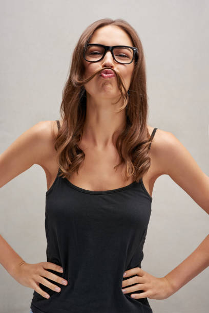 How do I look? Studio portrait of an attractive young woman posing with her hair over her lip against a grey background women movember mustache facial hair stock pictures, royalty-free photos & images