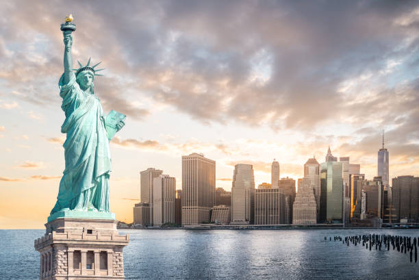 the statue of liberty with lower manhattan background in the evening at sunset, landmarks of new york city - new york city new york state skyline city imagens e fotografias de stock