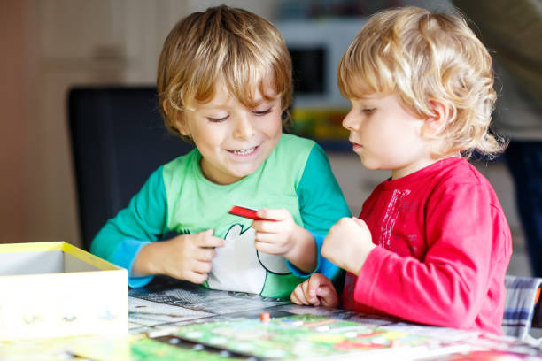 2 つの小さな金髪の子供男の子一緒に遊んで板自宅でゲーム。楽しく面白い兄弟です。 - people child twin smiling ストックフォトと画像