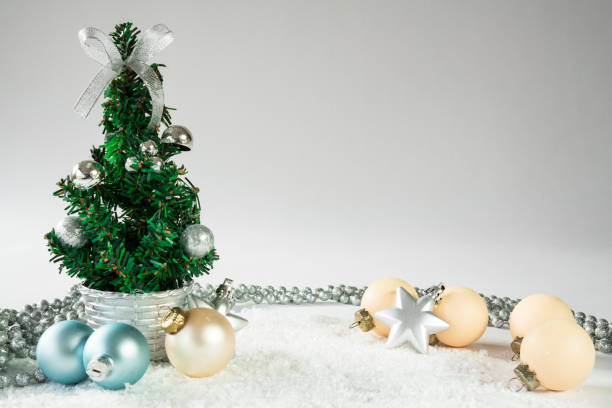 istock mini Christmas tree with blue and white balls, silver chain in snow, against white background, space for text 882983952