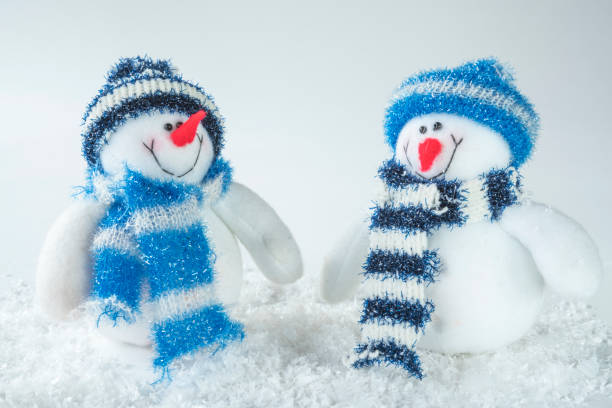 istock two stuffed dolls, snowman in snow, against white background 882984142